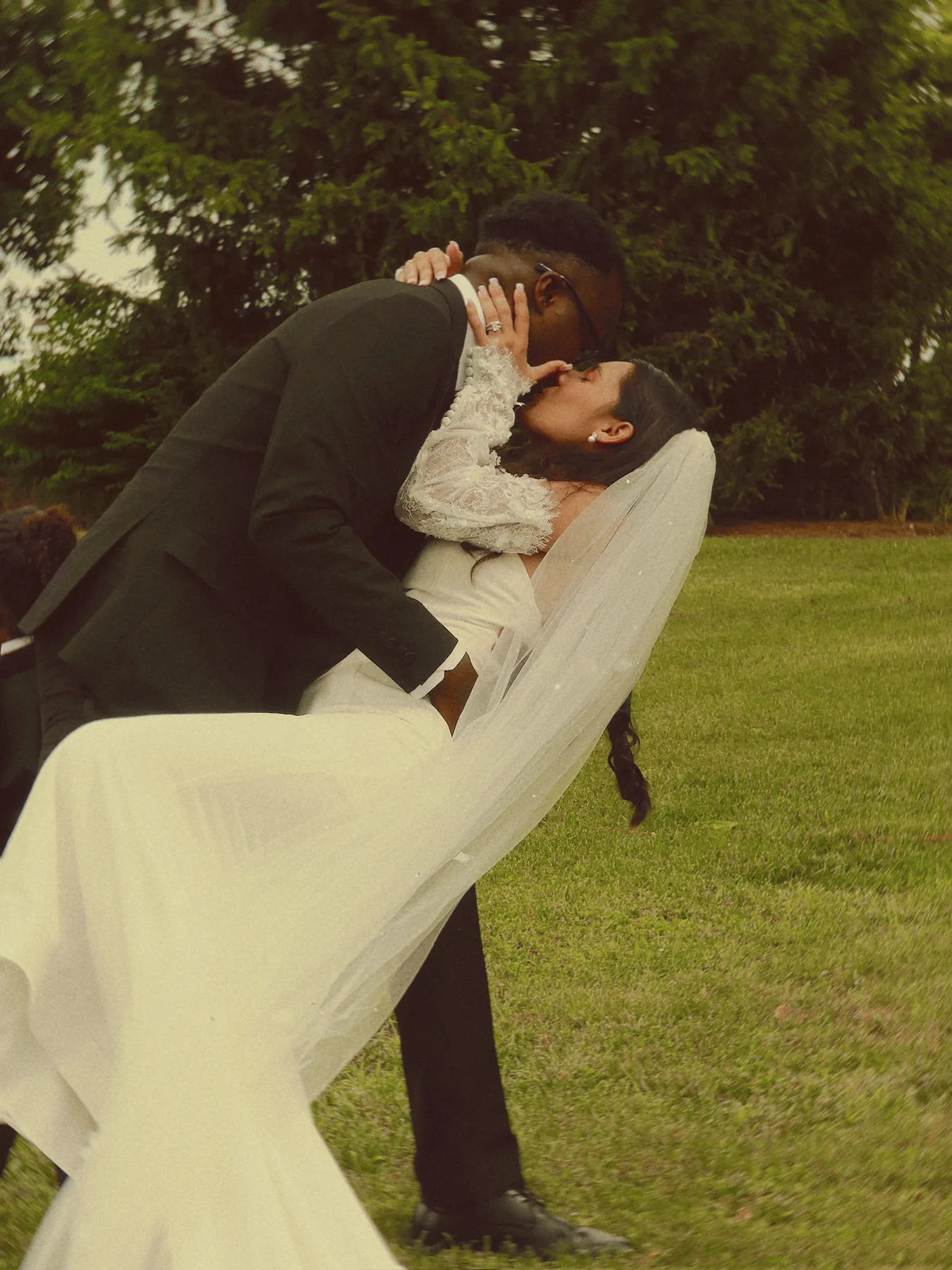 A dip kiss on the lawn, the veil trailing behind her