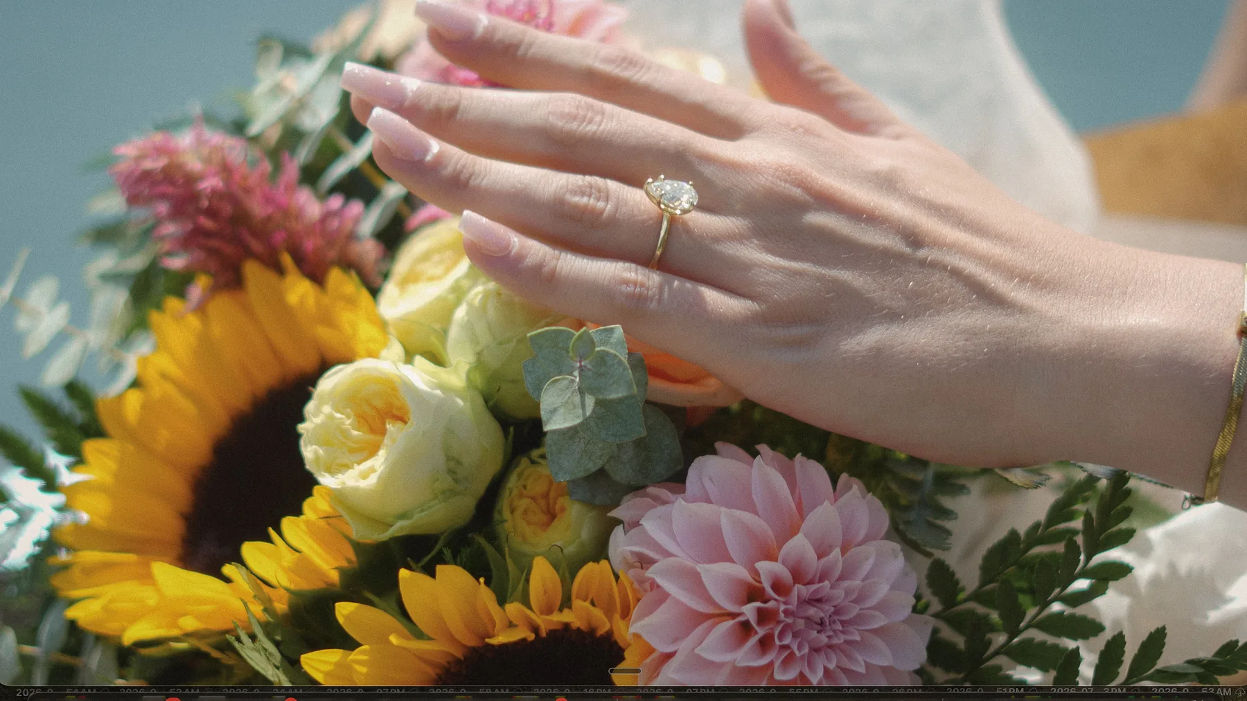 A ring on her hand over a bouquet of sunflowers and dahlias