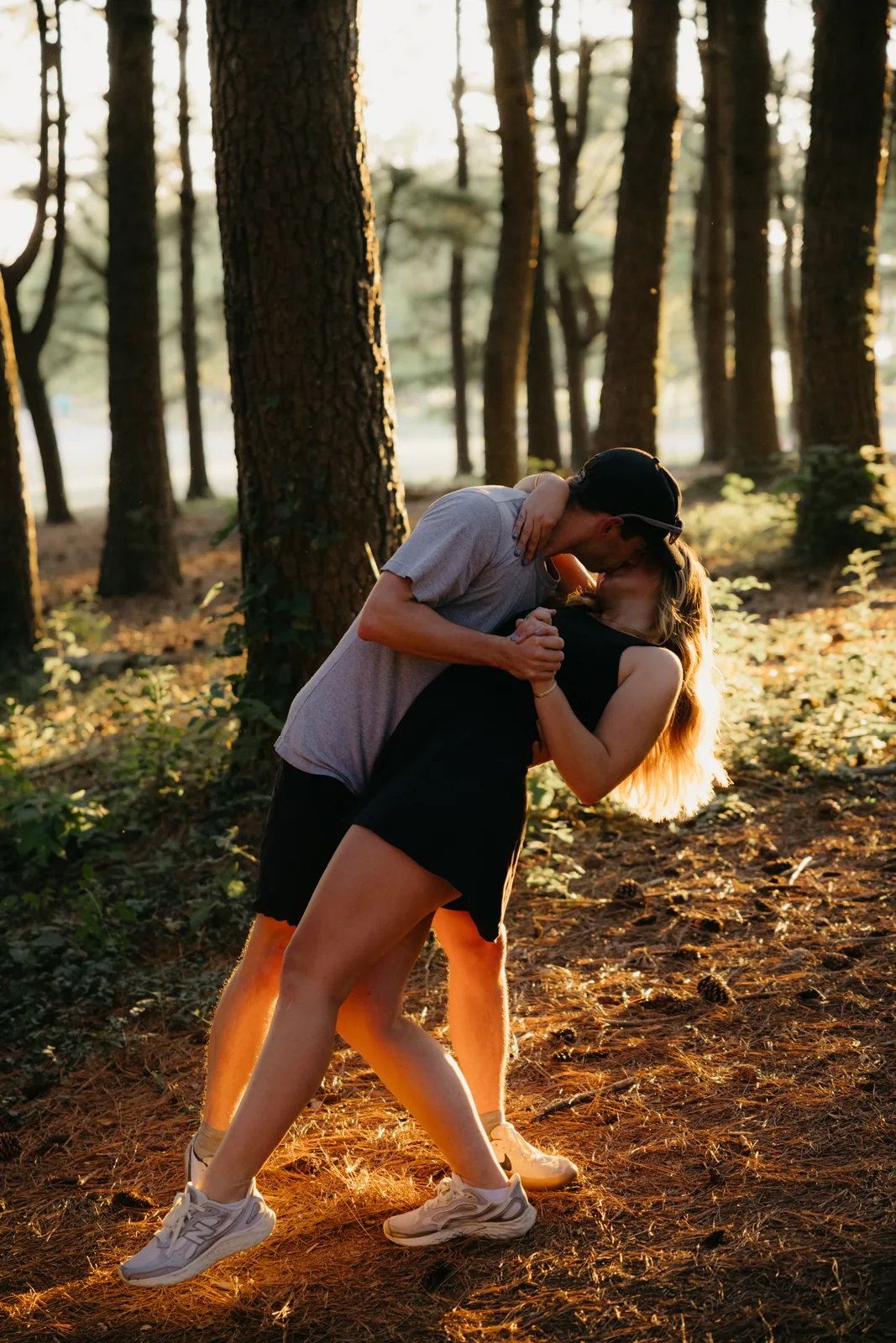 A dip kiss against a pine tree