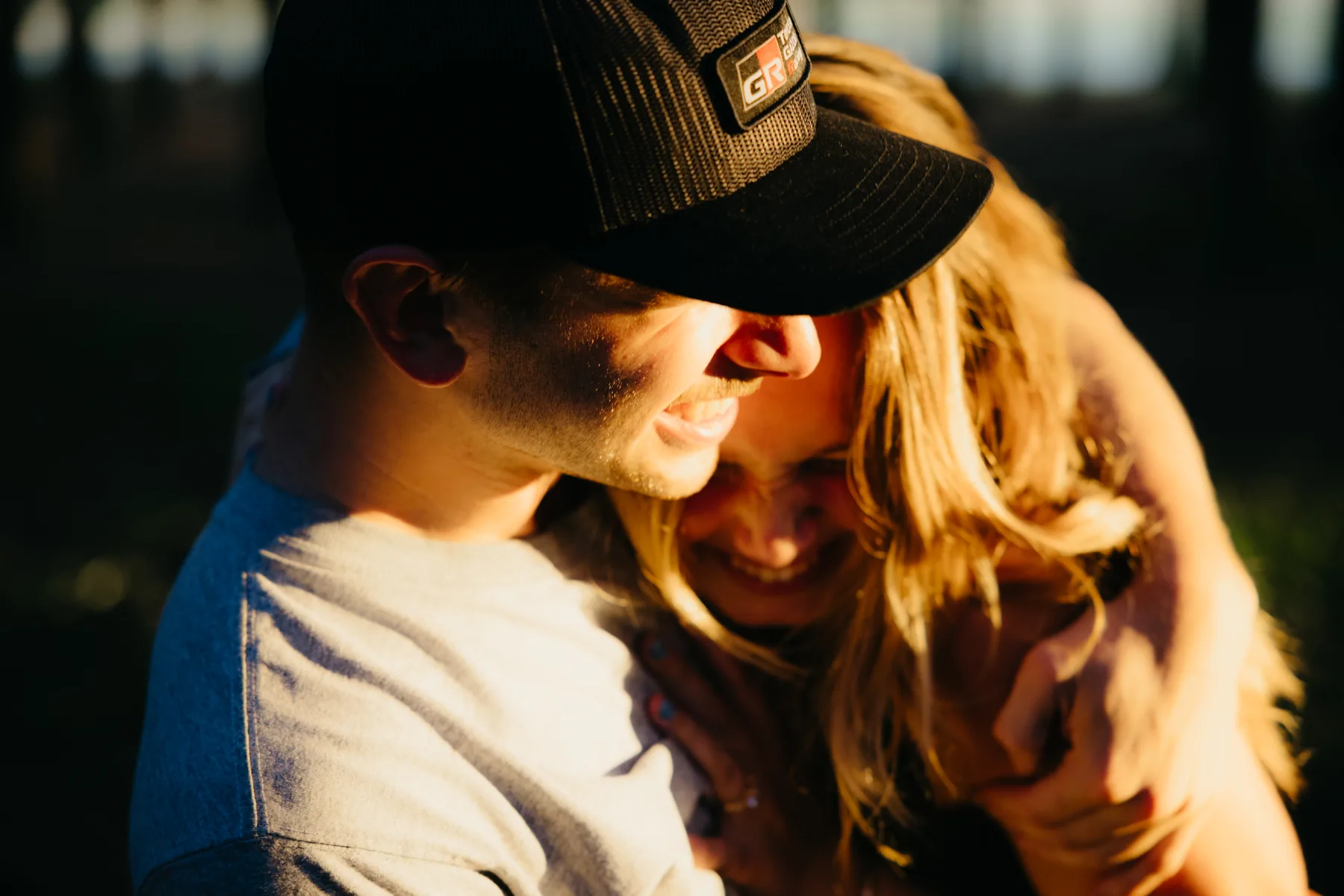 Two faces close together in warm late light, eyes closed, laughing