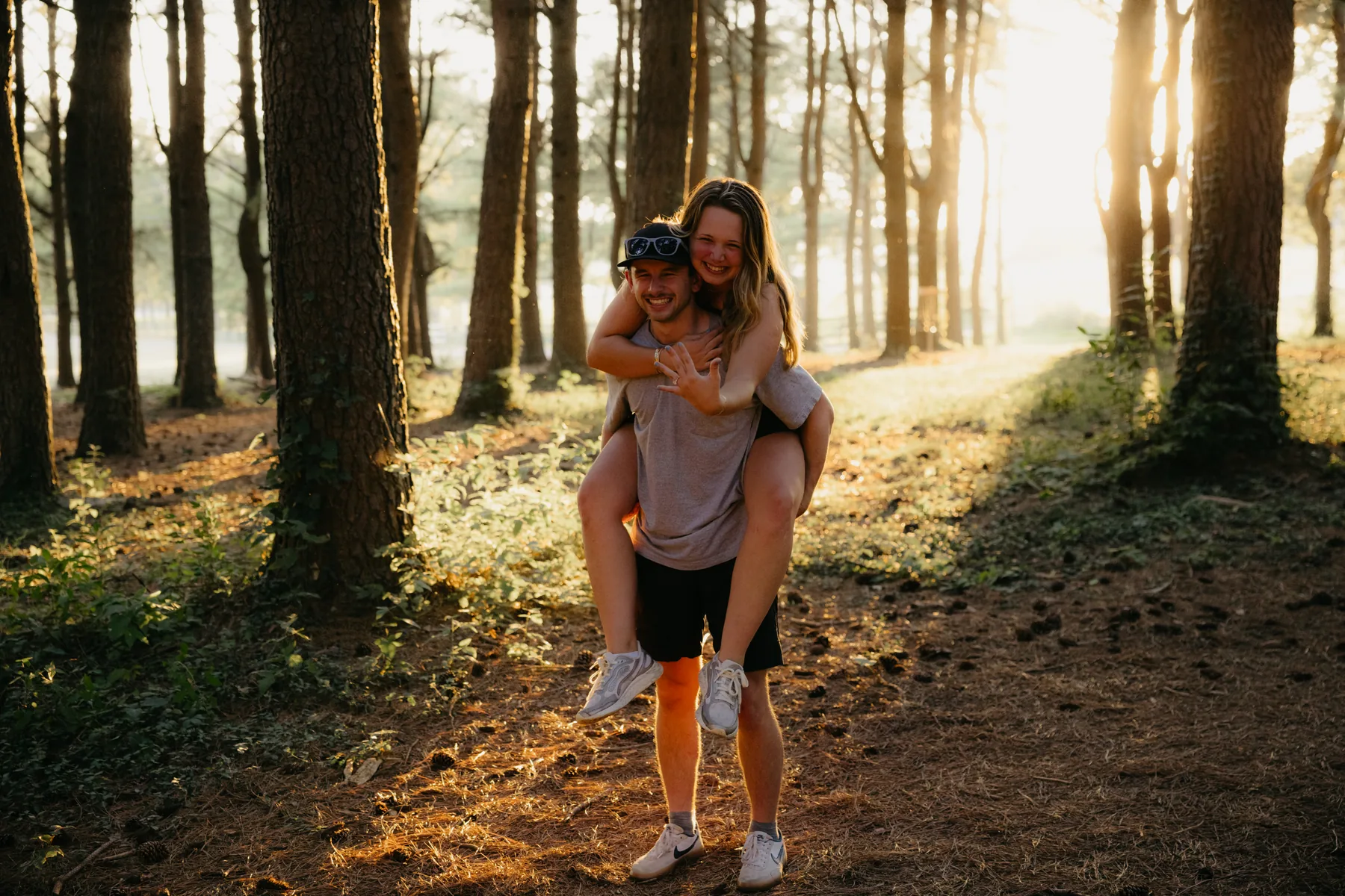 A piggyback ride through the pines with the sun flaring behind them