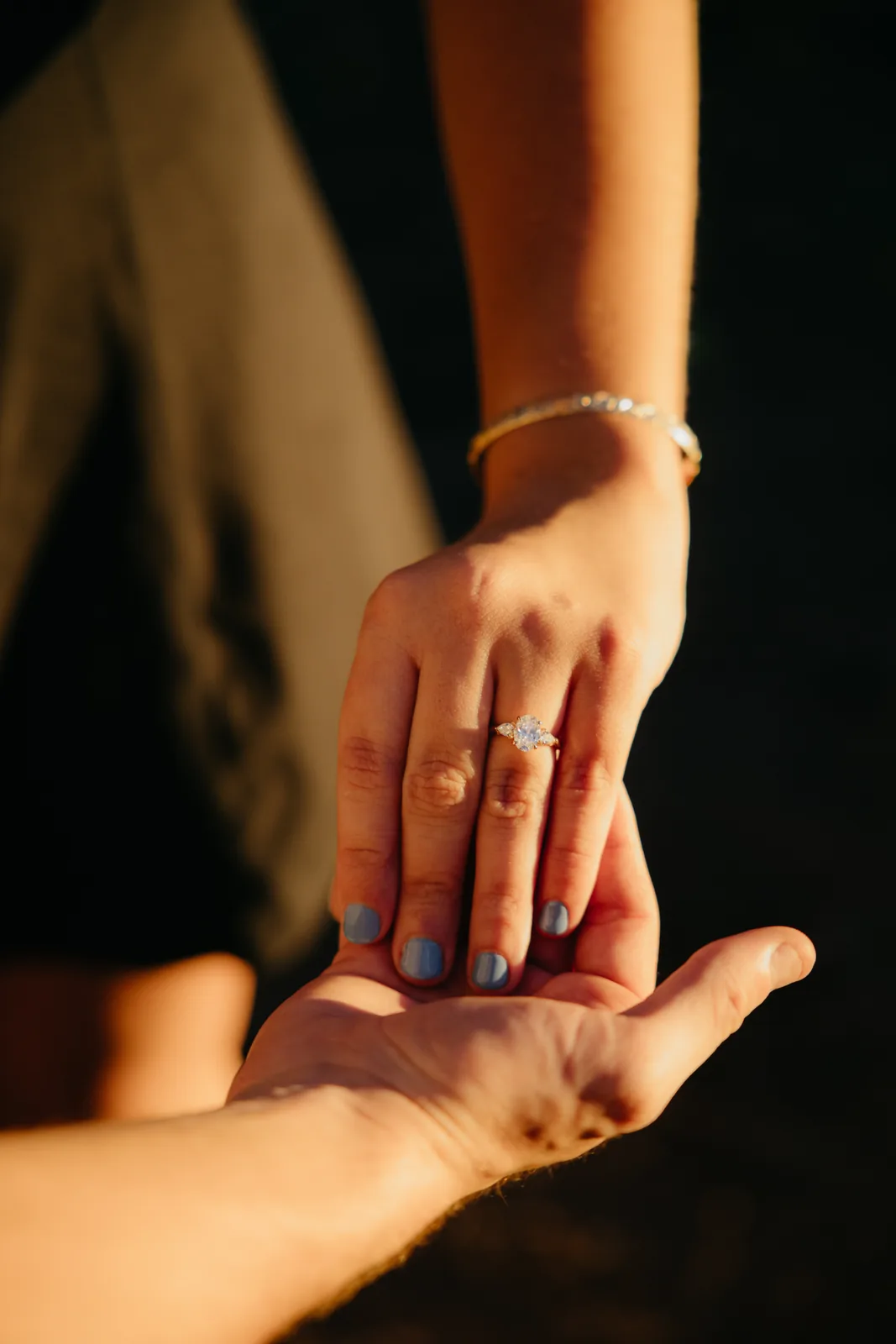 Her hand resting in his, the new ring in golden light