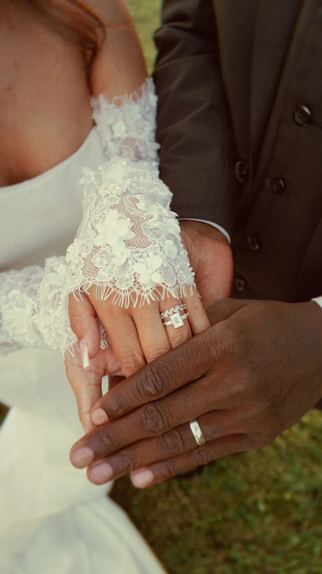 Her hand in his, the rings and the lace sleeve up close