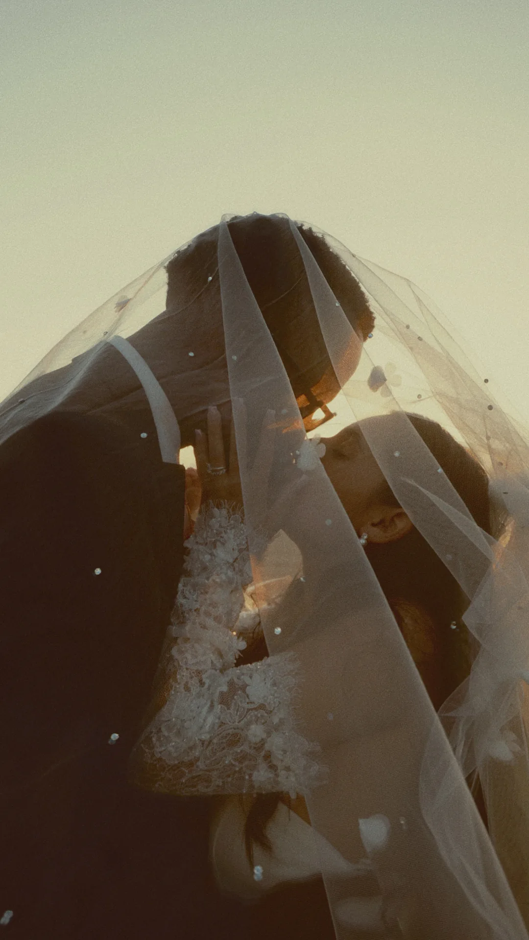 A kiss under the veil against the evening sky