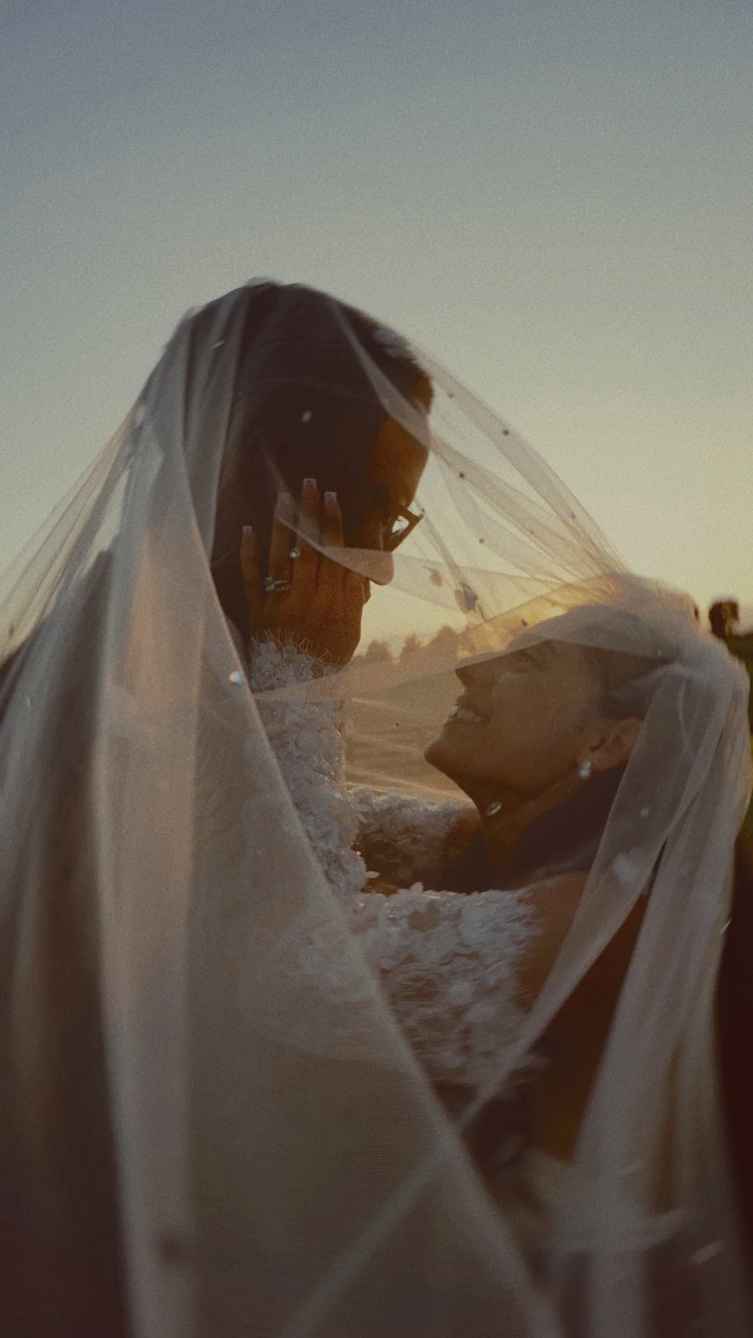 Her hand on his face under the veil, laughing, right after the ceremony
